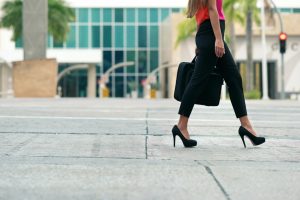 Cropped view of business woman walking in city street with laptop bag, commuting and going to work in the morning. Copy space, waist down